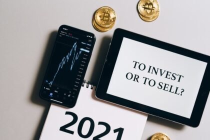 Overhead view of tablet, smartphone with chart, Bitcoin coins symbolizing investment choices for 2021.