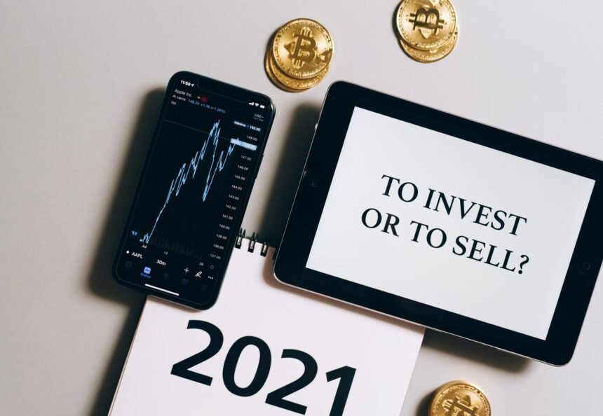 Overhead view of tablet, smartphone with chart, Bitcoin coins symbolizing investment choices for 2021.