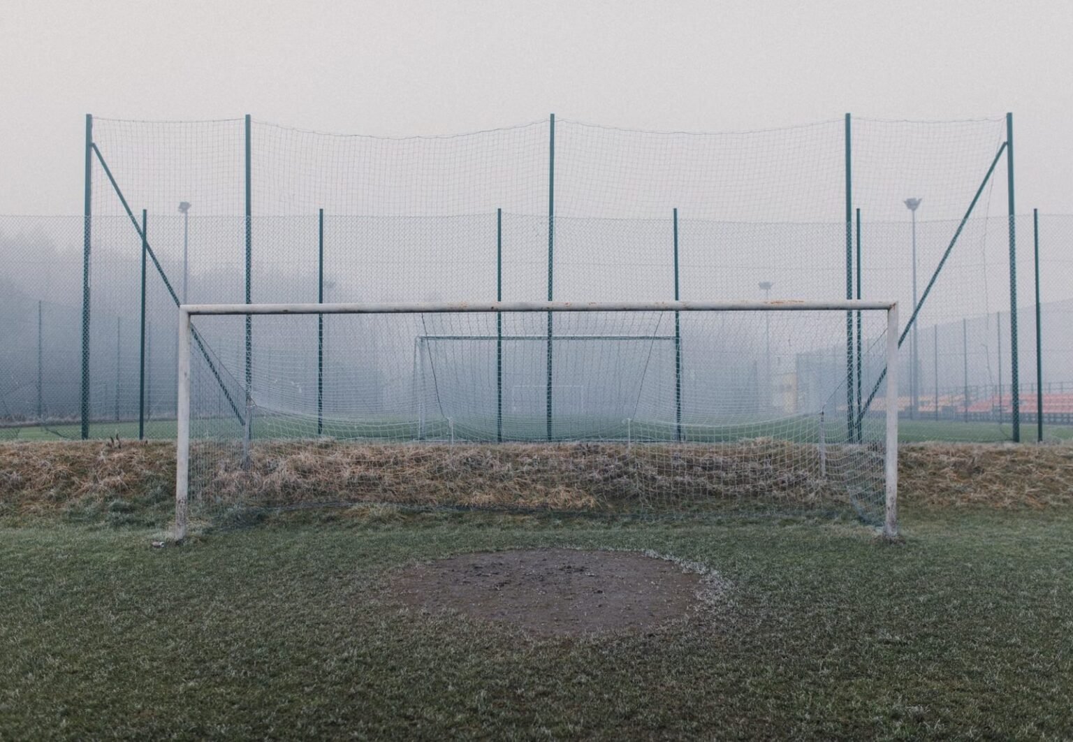 Misty football field featuring a frosty goal post and fog enveloping the sports ground.