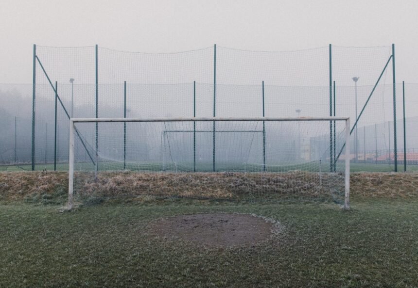 Misty football field featuring a frosty goal post and fog enveloping the sports ground.