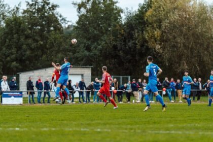 Players in blue and red compete intensely on a football field in France, capturing the spirit of the game.