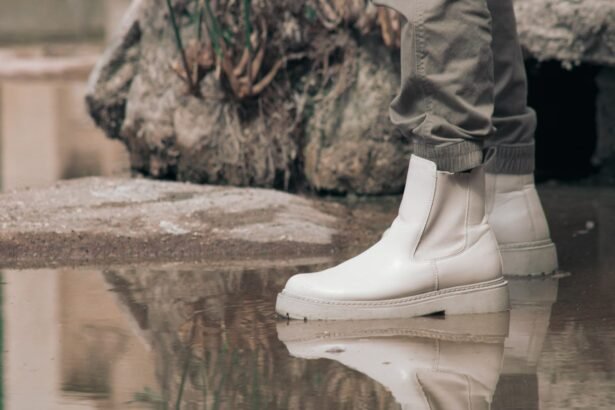 White Chelsea boots in a puddle with a rocky outdoor background, showcasing a stylish and reflective moment.