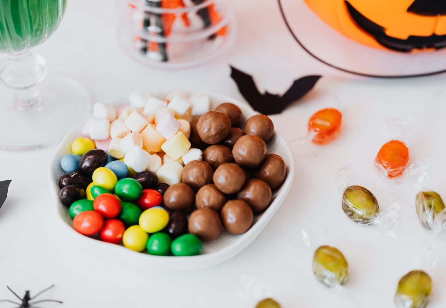 Festive Halloween candy assortment with chocolate, marshmallows, and jack-o'-lantern decor.