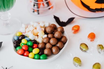 Festive Halloween candy assortment with chocolate, marshmallows, and jack-o'-lantern decor.