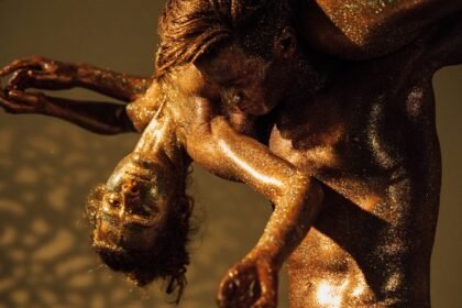 Dramatic dance performance with glitter-covered dancers in an artistic pose.