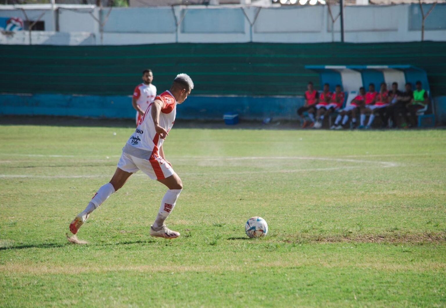 Male soccer player in action on the field during a sunny day match.