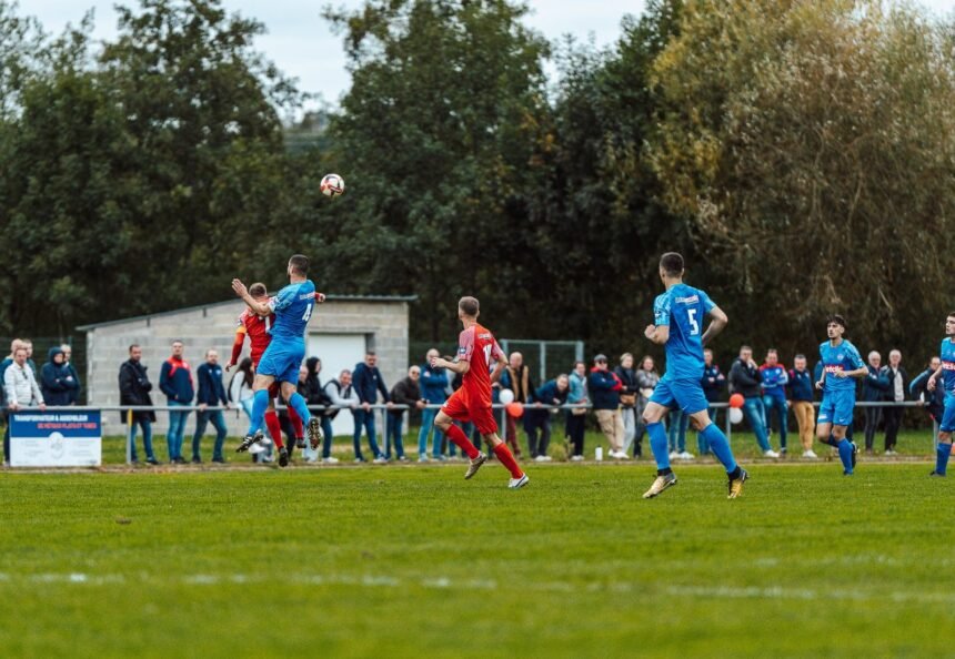Players in blue and red compete intensely on a football field in France, capturing the spirit of the game.