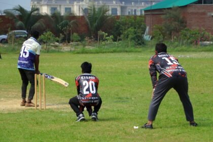 Cricket players in action on a sunny day at an outdoor field.