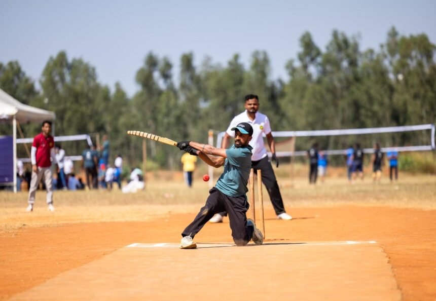 Cricket player skillfully hitting a ball during a lively outdoor match on a sunny day.