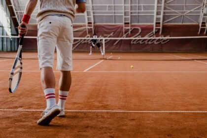 Players competing in a tennis match on an indoor clay court.