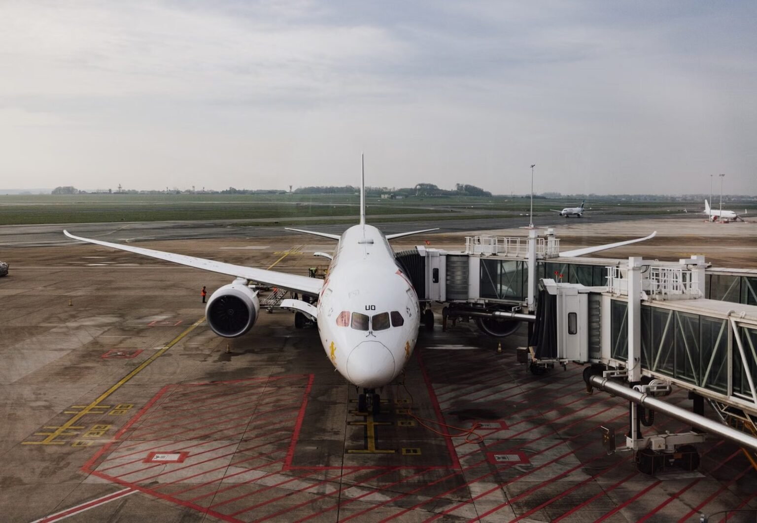 A modern jet airplane docked at an airport terminal gate, ready for boarding on a cloudy day.