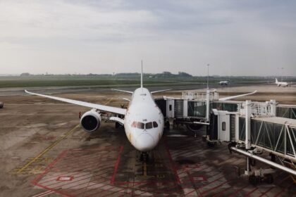 A modern jet airplane docked at an airport terminal gate, ready for boarding on a cloudy day.