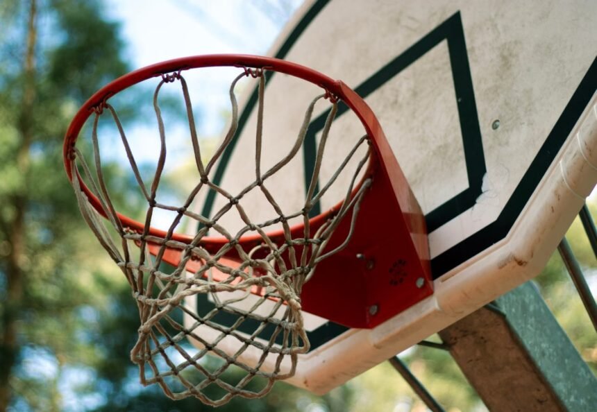 A detailed view of a basketball hoop and net against a blurred outdoor background, emphasizing a sporty feel.