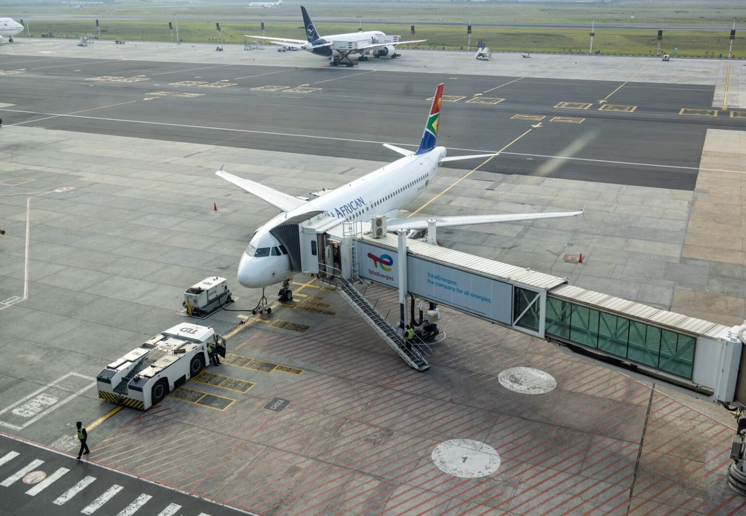 South African Airways plane docked at a gate in an airport, captured from an aerial view.