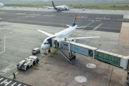 South African Airways plane docked at a gate in an airport, captured from an aerial view.