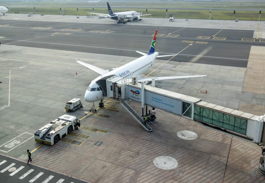 South African Airways plane docked at a gate in an airport, captured from an aerial view.