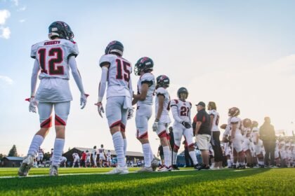 A high school football team lines up on the field, ready for their match.