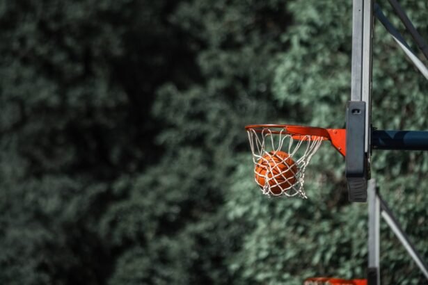 Close-up of a basketball scoring through a hoop outdoors with lush green background.