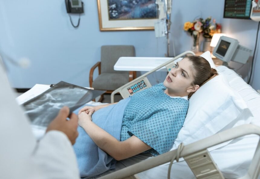 Caucasian woman in hospital bed receiving care from healthcare professional.