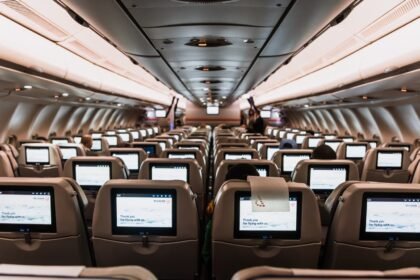 Comfortable airplane cabin interior featuring in-flight entertainment screens on all seats.