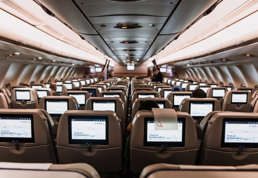 Comfortable airplane cabin interior featuring in-flight entertainment screens on all seats.