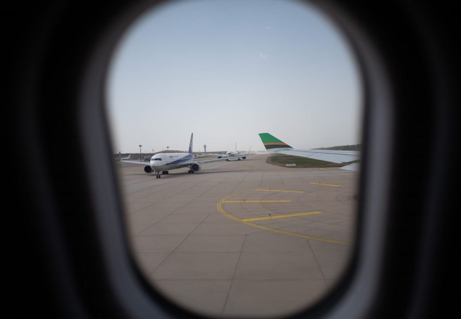 Airplane seen through a window, parked on the airport runway, capturing a travel moment.