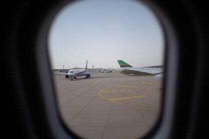 Airplane seen through a window, parked on the airport runway, capturing a travel moment.