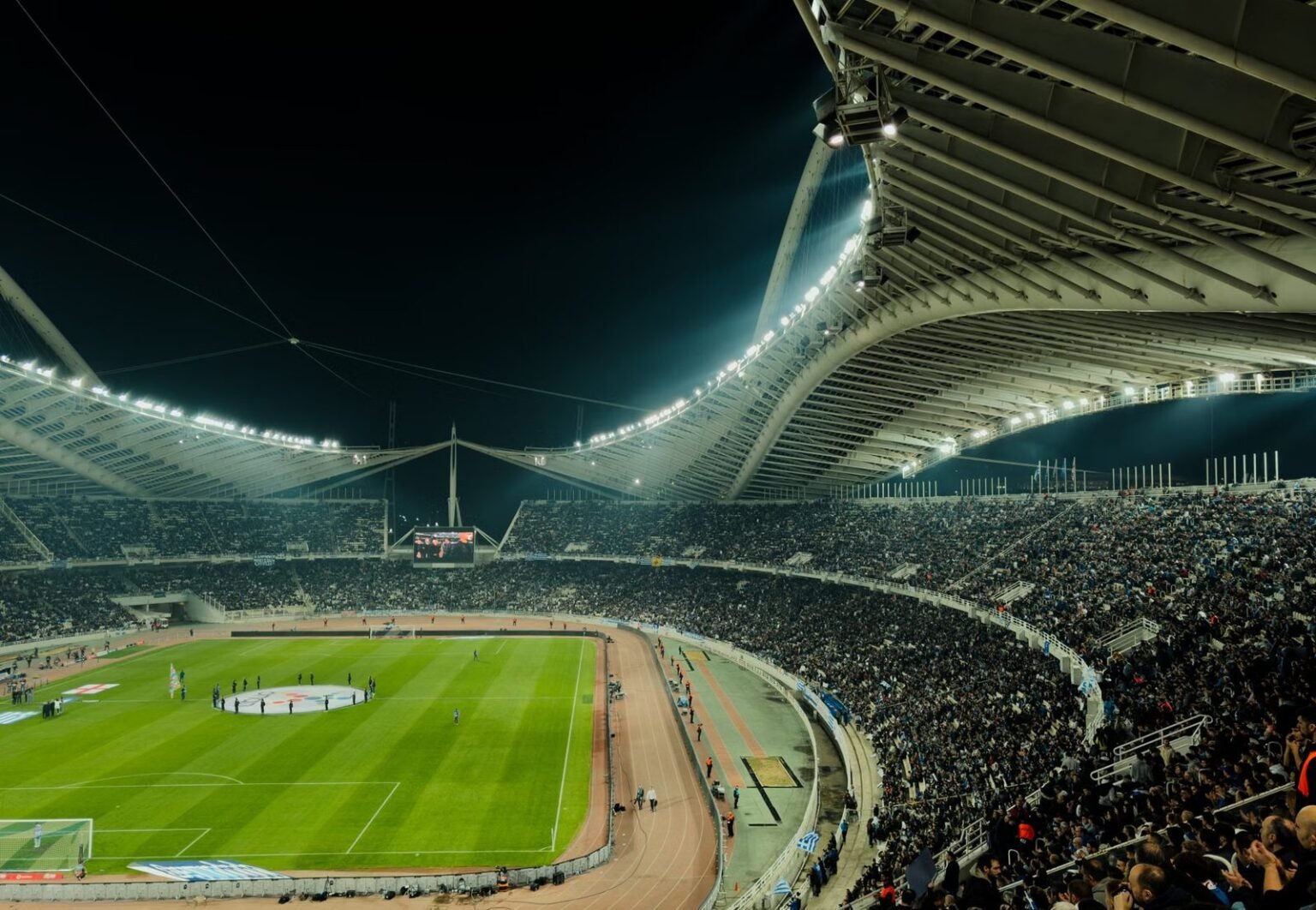 A crowded soccer stadium under bright lights at night, capturing the excitement of a live sports event.