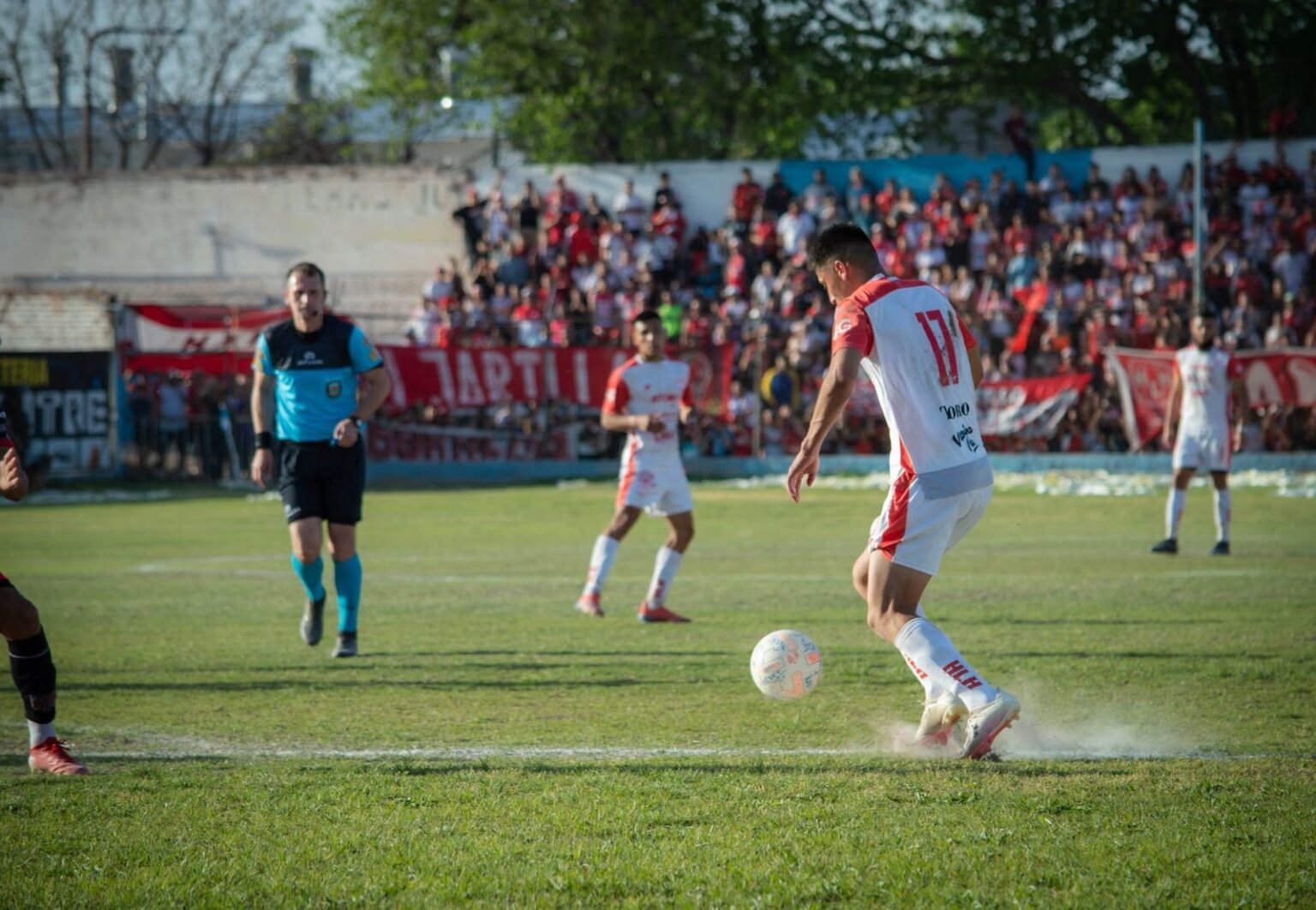 Intense football match showcasing players' skills on a sunny day in Mendoza, Argentina.