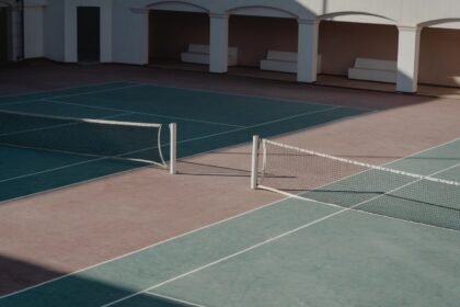 A deserted tennis court with shadows casting over the net, creating a serene atmosphere.
