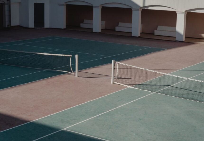 A deserted tennis court with shadows casting over the net, creating a serene atmosphere.