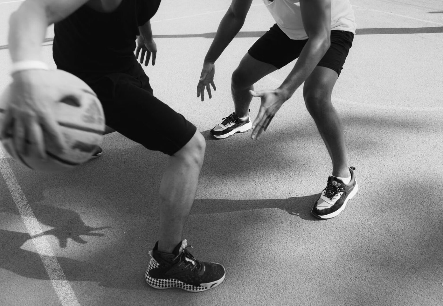 Monochrome image capturing intense basketball action and dribbling on the court.