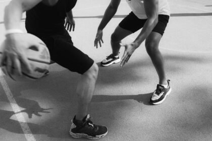 Monochrome image capturing intense basketball action and dribbling on the court.