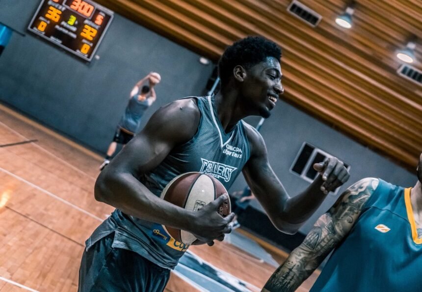 Engaging moment of basketball players during an indoor training session on a wooden court.