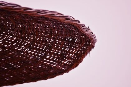 Detailed close-up of an intricately woven wicker basket against a soft pink background.