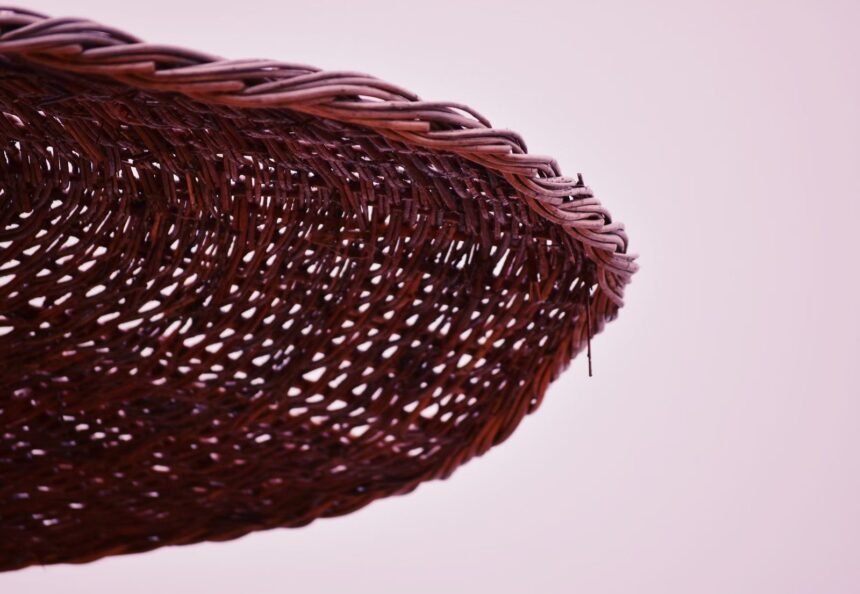 Detailed close-up of an intricately woven wicker basket against a soft pink background.