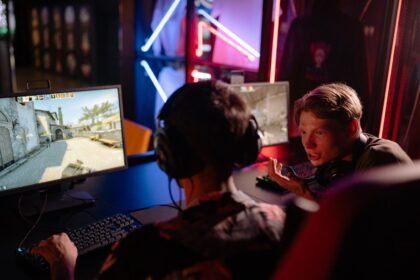Two gamers engaged in a heated video game session surrounded by neon lights and computer screens.